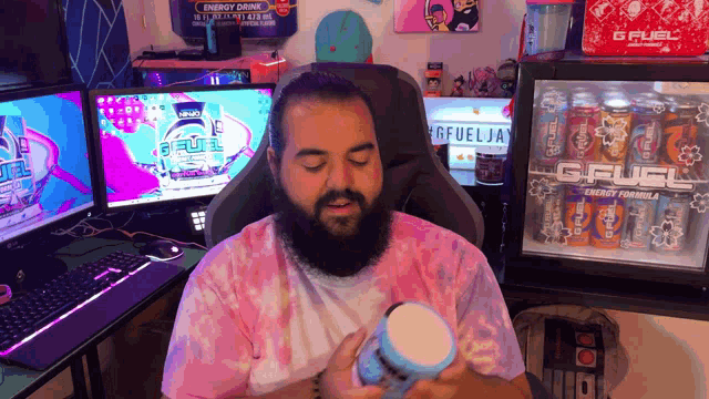 a man sitting in front of a gfuel energy drink fridge