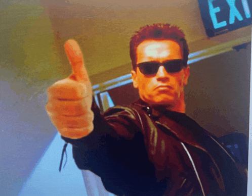 arnold schwarzenegger is giving a thumbs up in front of an exit sign