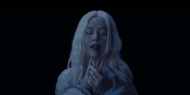 a woman with white hair is holding a blue blanket in the dark