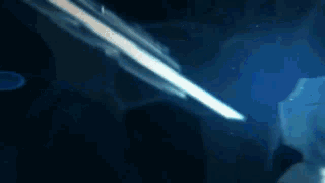 a person is holding a sword in a dark room with a blue light coming from it .