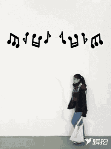 a woman is walking in front of a white wall with music notes written on it