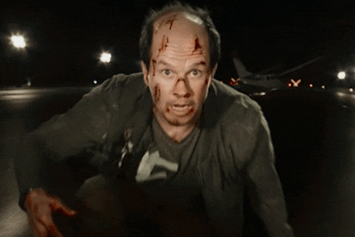 a man with blood on his face is walking down a street at night with a plane in the background .