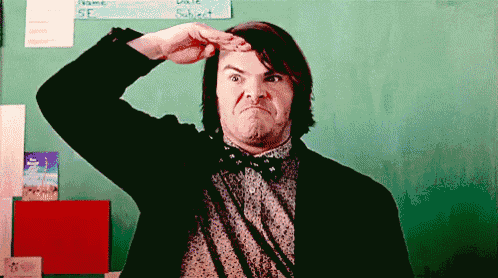 a man in a suit and bow tie is making a funny face in front of a chalkboard .