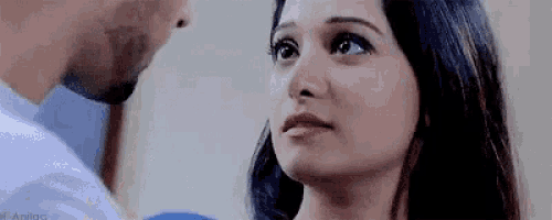 a man and a woman are kissing and the woman is looking at the man .