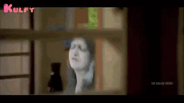 a woman is standing in front of a window in a room looking out .