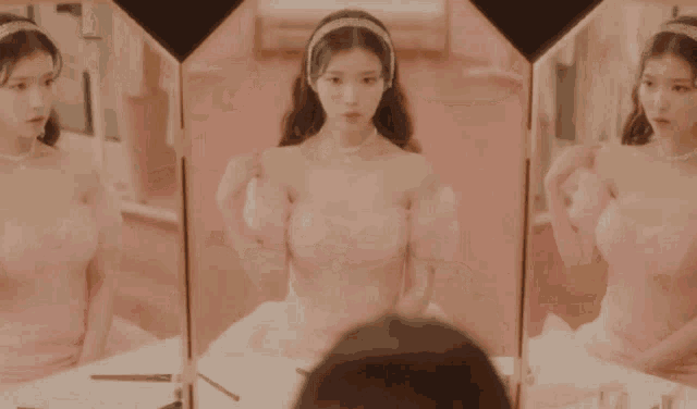 a woman in a pink dress is standing in front of a mirror