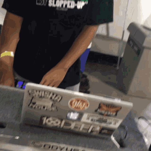 a man wearing a black shirt that says " i 'm slopped up " is using a laptop