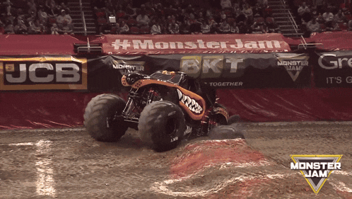 a monster jam sign is behind a monster truck on a dirt track
