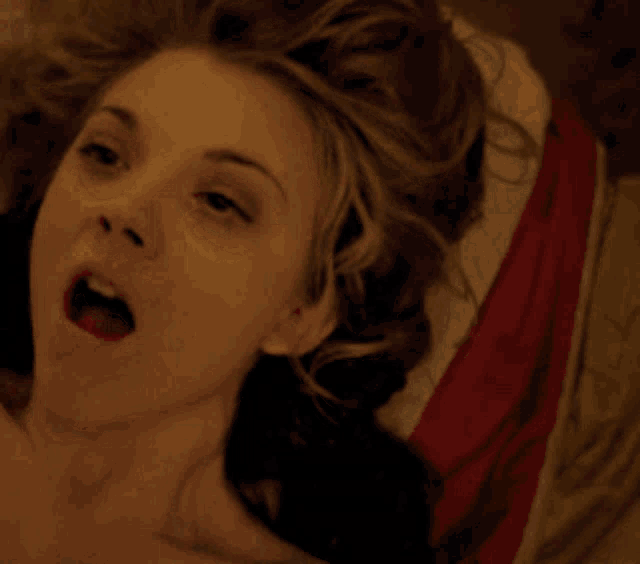 a close up of a woman laying on a bed with her mouth open