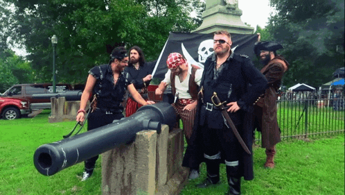 a group of men dressed in pirate costumes standing around a cannon