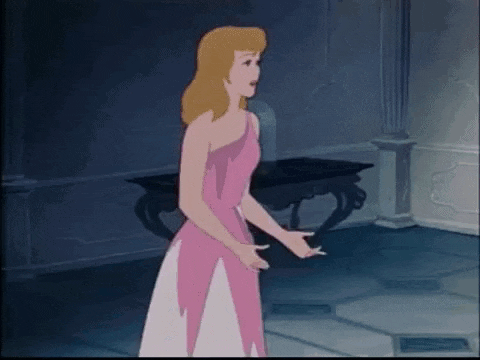 cinderella is wearing a pink dress and standing in a room in front of a table .