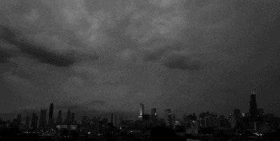 a black and white photo of a city skyline at night with a stormy sky .