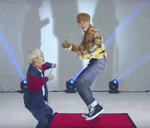 two men are dancing on a red carpet on a stage in front of a crowd .