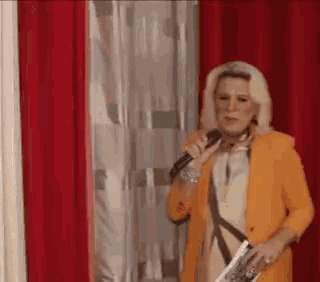 a woman in a yellow jacket is holding a microphone and a magazine .