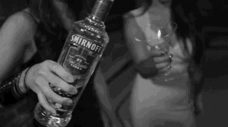 a black and white photo of a woman holding a bottle of smirnoff vodka .