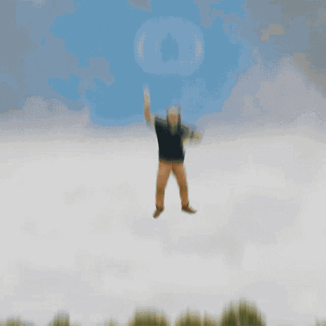 a man in a black shirt and brown pants is jumping in the air