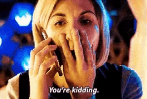a woman is covering her mouth while talking on a cell phone and saying `` you 're kidding . ''