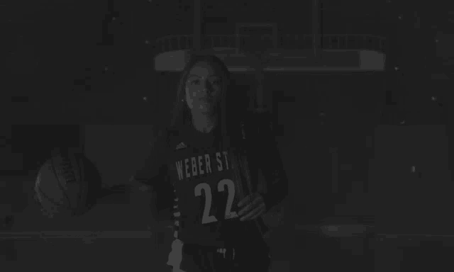 a black and white photo of a woman sitting on the floor in front of a basketball hoop .
