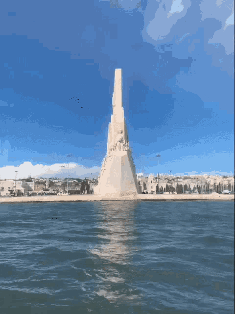 a large statue in the middle of a body of water with a city in the background