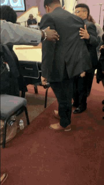 a man in a suit is hugging another man on a red carpet