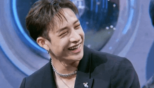 a close up of a man wearing a suit and a necklace while smiling .