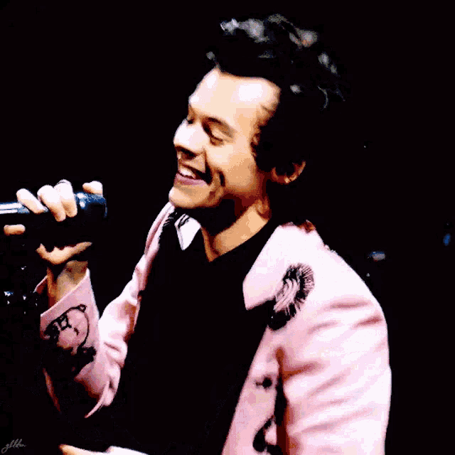 a man in a pink suit is holding a microphone