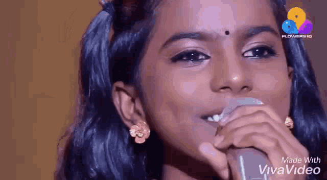 a little girl is singing into a microphone on a stage .