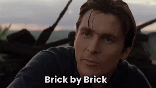 a close up of a man 's face with the words " brick by brick " below him