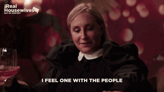 a woman holding a glass of wine with the words i feel one with the people above her