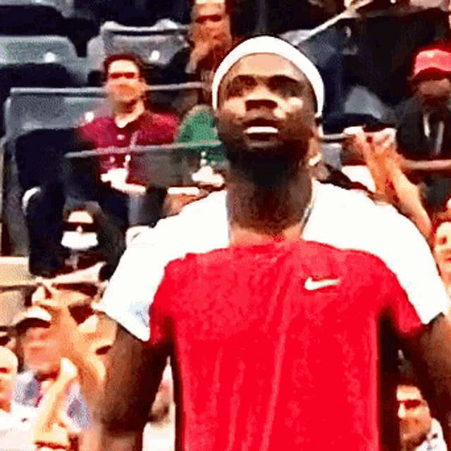 a man in a red nike shirt stands in front of a crowd of people