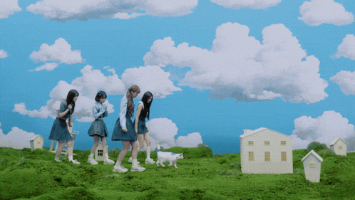 a group of girls walking on a grassy hill with a white house in the foreground