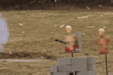 a man is shooting a gun at a target with a skeleton in the foreground