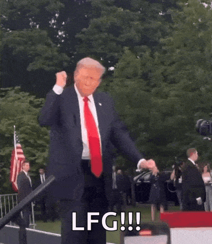 donald trump is dancing in front of a crowd while wearing a suit and tie and a red tie .