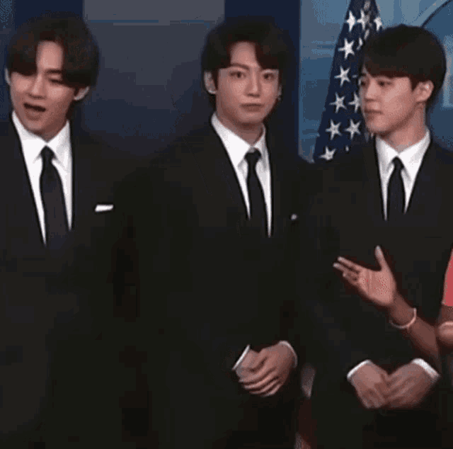 three men in suits and ties are standing next to each other .
