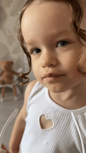 a little girl wearing a white top with a heart cut out