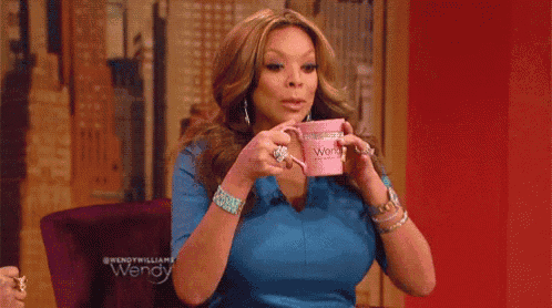 a woman in a blue shirt is drinking from a pink mug with the word wendy on it