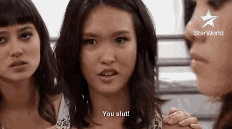 a group of three women are standing next to each other and one of them is talking to the other .