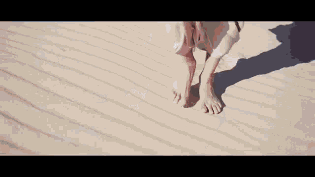a woman in a white dress is walking barefoot on a sandy beach .