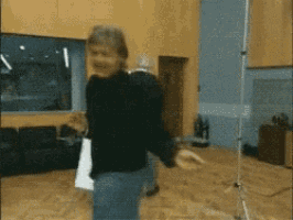 a man in a black shirt is standing on a wooden floor