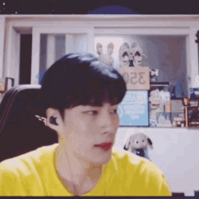 a man wearing a yellow t-shirt is sitting in front of a computer screen .