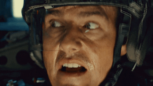 a close up of a man wearing a helmet with a surprised look on his face
