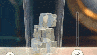 a glass filled with ice cubes is sitting on a table .