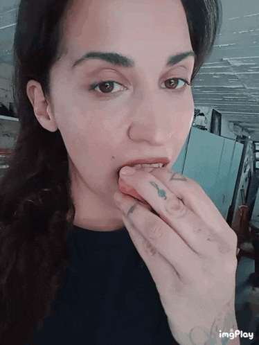 a woman with tattoos on her fingers is eating a piece of food