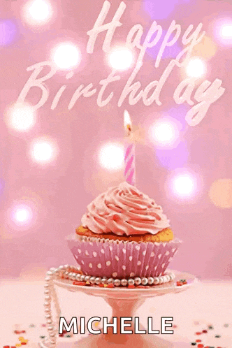 a cupcake with a pink frosting and a lit candle is on a plate with the name michelle on it