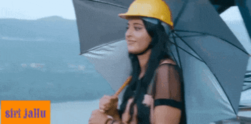 a woman wearing a hard hat is holding an umbrella and smiling