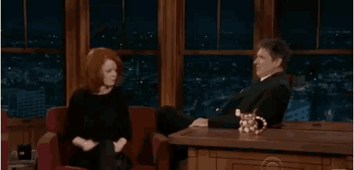 a man and a woman are sitting at a table in a room .