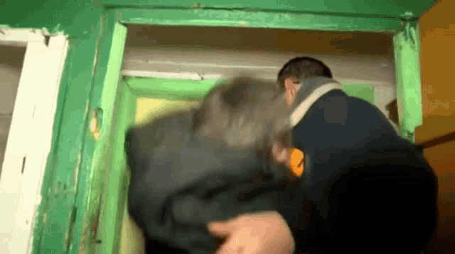 a man in a black jacket is carrying another man in a black jacket through a doorway .