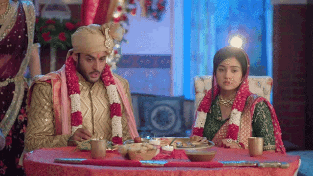 a bride and groom are sitting at a table eating food