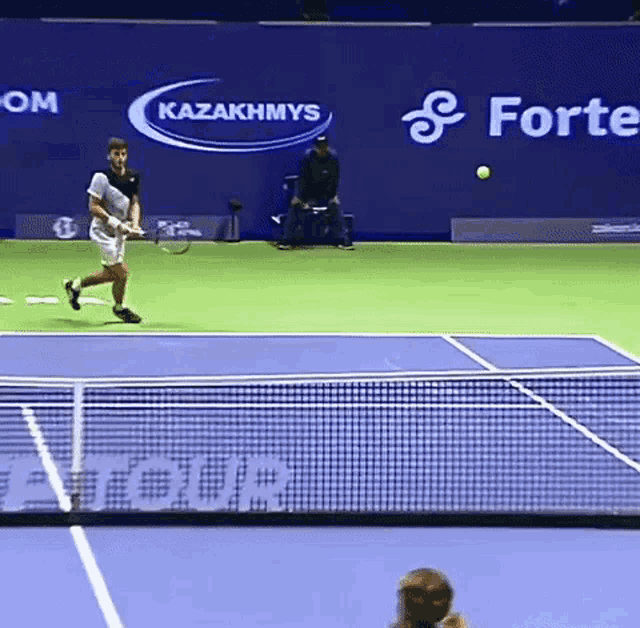 a tennis player is swinging a racket on a court with an advertisement for kazakhmys