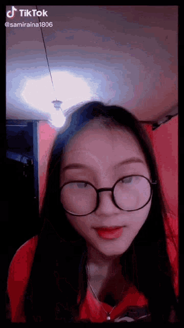 a girl wearing glasses and a red shirt is on a tiktok video